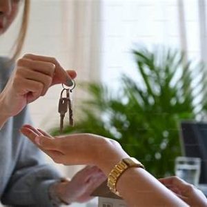 Real estate agent handing house keys to client—symbolizes safe closing and trusted brokerage post-iPro Realty closure.